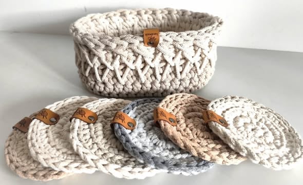 Woven rope coasters in beige and gray tones with leather tags, displayed with a matching storage basket